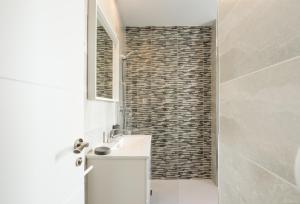ein Badezimmer mit einem weißen Waschbecken und einer Ziegelwand in der Unterkunft MalagaSuite Malagueta Impressive Views in Málaga