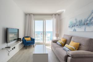 ein Wohnzimmer mit einem Sofa und einem TV in der Unterkunft MalagaSuite Malagueta Impressive Views in Málaga