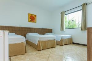 three beds in a room with a window at Hotel Holiday Foz in Foz do Iguaçu
