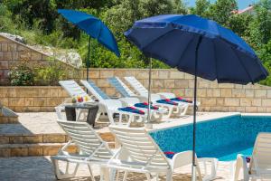 Un grupo de sillas y sombrillas junto a una piscina en Apartments Villa Elena 3, en Cavtat