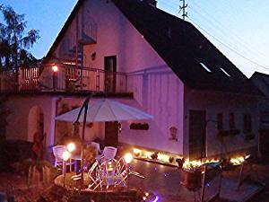 budynek z patio z krzesłami i parasolem w obiekcie Ferienhaus Wasgaublick w mieście Bundenthal