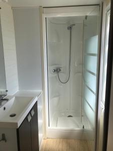 a white bathroom with a shower and a sink at Camping Horizon Bar in Frontignan