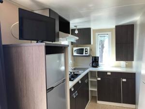 a kitchen with brown cabinets and a tv on top at Camping Horizon Bar in Frontignan