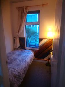 a small bedroom with a bed and a window at Simon's Cosy House in Bangor