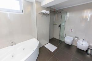 a bathroom with a tub and a toilet and a shower at Demi Hotel in Sarandë