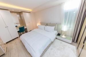 a white bedroom with a white bed and a desk at Demi Hotel in Sarandë
