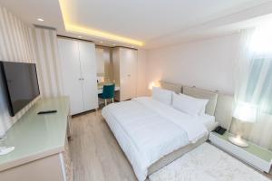 a hotel room with a white bed and a television at Demi Hotel in Sarandë