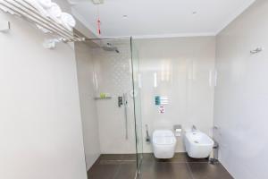 a bathroom with a shower and a toilet and a sink at Demi Hotel in Sarandë