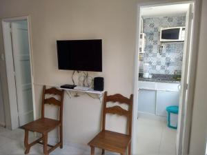 a room with two chairs and a television on a wall at Andar Alto Frente Ipanema in Rio de Janeiro