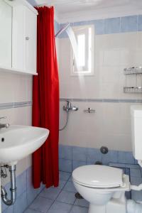 y baño con aseo y cortina de ducha roja. en Cozy & peaceful apartment in Chalki en Khalkíon