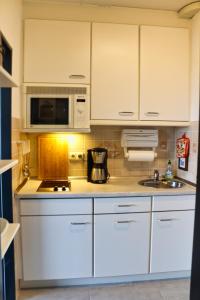 Una cocina con gabinetes blancos y un fregadero. en Südstrandperle, en Fehmarn