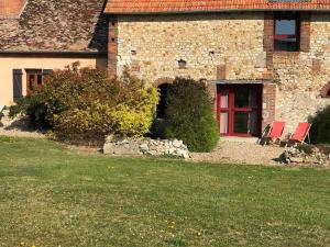 une maison en briques avec deux chaises et une porte rouge dans l'établissement Résidences Le Clos du Manoir - Self Cooking, à Gauciel