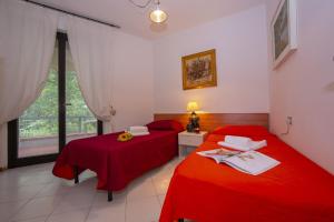 2 letti rossi in una camera con finestra di Francesca 2 400mt From Sea - Happy Rentals a Massa