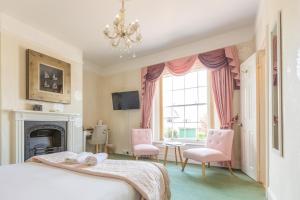 a bedroom with a bed and chairs and a fireplace at Beaufort Lodge in Taunton