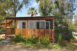 Cabaña pequeña con valla de madera en Villaggio Camping Torre Salinas en Muravera