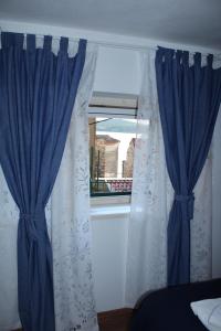 a window with blue and white curtains in a room at Karmelita's place -studio in Šibenik