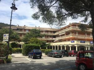 un grand bâtiment avec des voitures garées dans un parking dans l'établissement MINERVA, à Deiva Marina