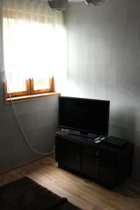 TV de pantalla plana en un stand en una habitación con ventana en Domek w Borkowie, en Borkowo
