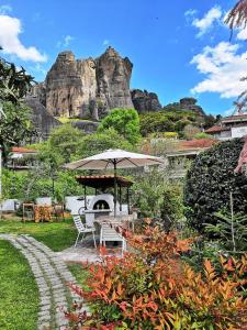 a garden with an umbrella and a table and chairs at Sotiris Idyllic Garden House in Kalabaka