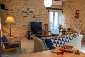 uma sala de estar com um sofá e uma televisão em Le Petit Manoir de Vitrac em Vitrac