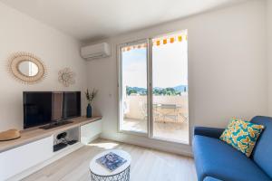 Una sala de estar con un sofá azul y un televisor. en Studio del Sol, en Saint-Cyr-sur-Mer
