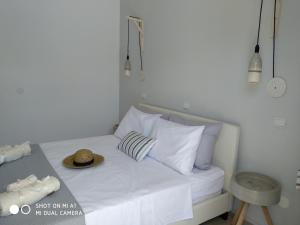 a bed with white pillows and a hat on it at Paleokastritsa Studios - Sun's Gift Spiros in Paleokastritsa
