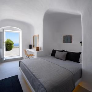 a white bedroom with a bed and a window at Delilah Villa by Senses Collection in Pyrgos