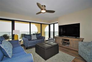 a living room with a blue couch and a flat screen tv at Ocean Vista Condo Unit #1201 in South Padre Island
