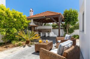 een patio met rieten meubels en een buitengrill bij ELENA HOUSE 2 in Gennadi