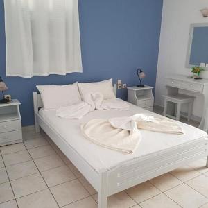 Una cama blanca con toallas en un dormitorio en Melissa Rooms, en Koufonisia