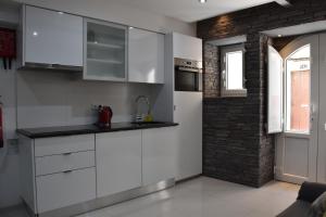 una cocina con armarios blancos y una pared de ladrillo en Home In the Sea, en Sesimbra