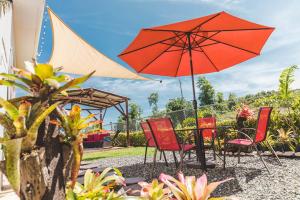 einen Tisch mit roten Stühlen und einem Regenschirm in der Unterkunft Eden's Garden in Isabela