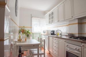 een keuken met witte kasten, een tafel en een wastafel bij Home By The Sea in Sesimbra
