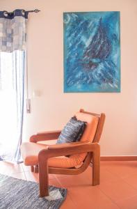 an orange chair in a room with a painting at Home By The Sea in Sesimbra