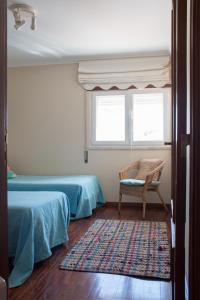 a bedroom with two beds and a chair and a window at Home By The Sea in Sesimbra