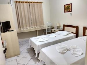 a hotel room with two beds and a television at Vinte Park Hotel in Bragança Paulista