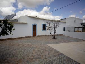 a white building with a tree in front of it at O Nosso Lar in Lagos