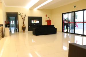 a living room with a black couch and a tv at Hotel Renascer in Terenos