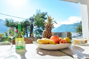 a bowl of fruit on a table with a bottle of wine at Waterfront Apartment Petrovina in Kotor