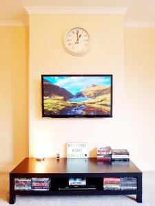 a living room with a tv and a clock on the wall at Three Bed Holiday Home in Glasgow in Glasgow