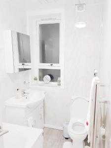 een witte badkamer met een toilet en een wastafel bij Three Bed Holiday Home in Glasgow in Glasgow