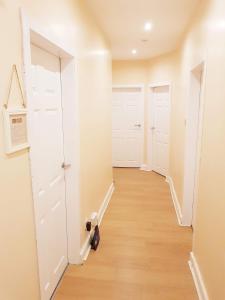 グラスゴーにあるThree Bed Holiday Home in Glasgowの白いドアと木製の床の廊下