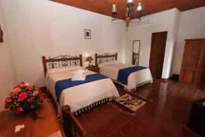 1 dormitorio con 2 camas y una mesa con flores en Parador Monte Carmelo, en Oaxaca City