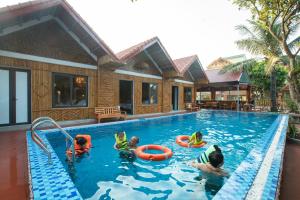 a group of children playing in a swimming pool at Tam Coc Charming Bungalow in Ninh Binh