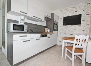 een keuken met witte kasten, een tafel en een magnetron bij Villa Doris Bng 8 Hanau in Heringsdorf