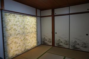 una camera con due finestre e un muro di mattoni di Lumiere De Bonnart a Okayama