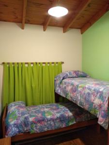 - une chambre avec 2 lits et un rideau vert dans l'établissement La casa del Titi, à Tandil