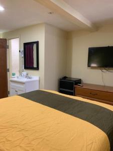 a hotel room with a yellow bed and a flat screen tv at Budget Inn Williamsville in Williamsville