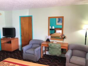 Habitación de hotel con 2 sillas y TV en Klamath Motor Lodge, en Yreka