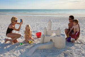 a group of people on the beach playing with a sand castle at Inn at Pelican Bay in Naples